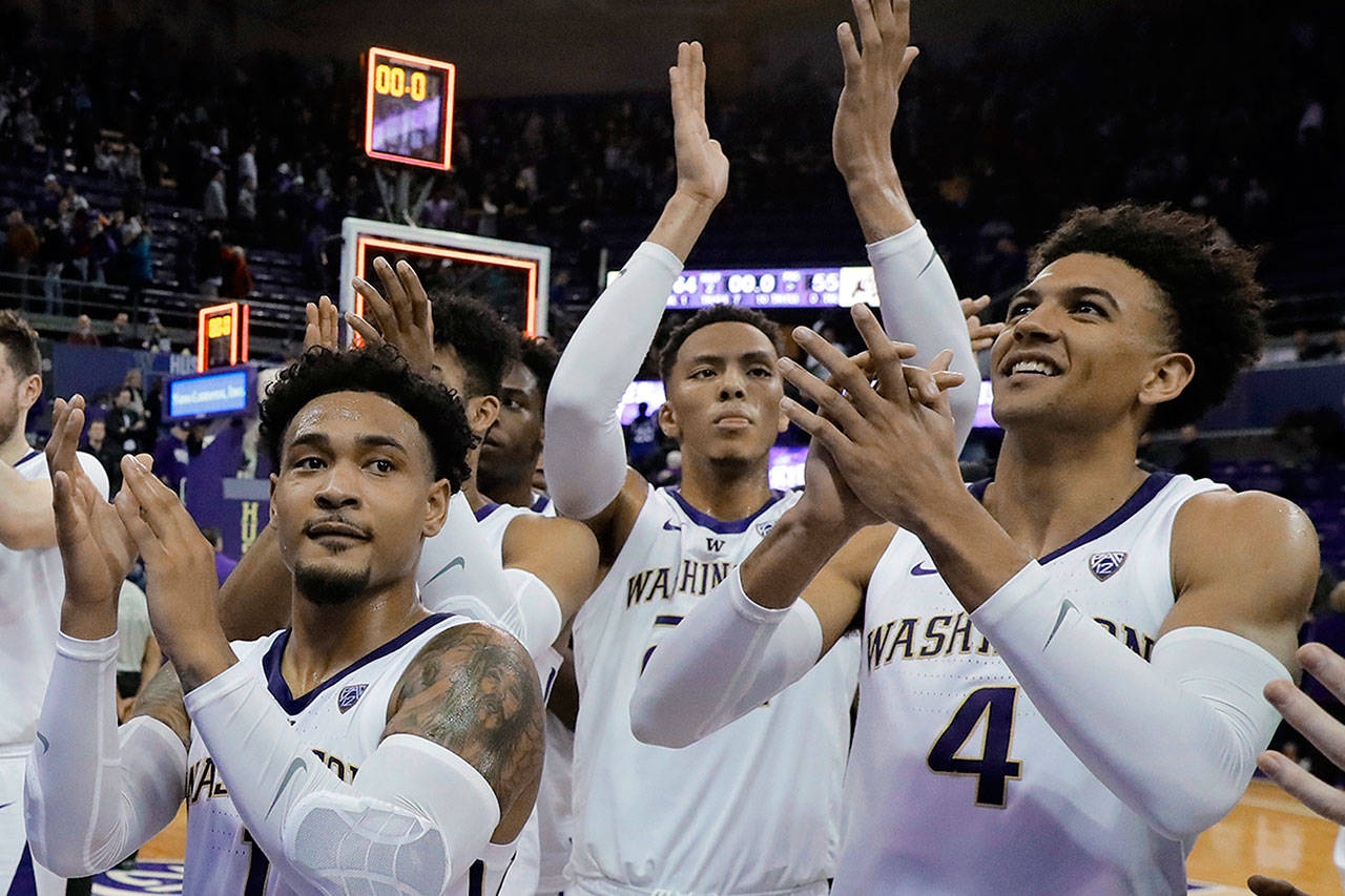Washington’s David Crisp (1), Dominic Green and Matisse Thybulle (4) celebrate in front of the student section after the team’s game against Colorado, on Feb. 23 in Seattle. Washington won 64-55. (Ted S. Warren / Associated Press)