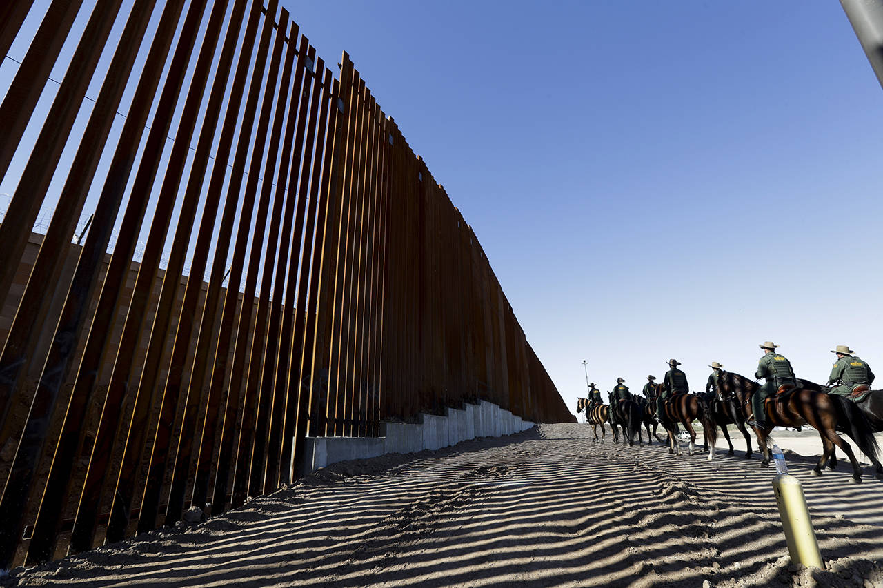 In this 2018 photo, mounted Border Patrol agents ride along a newly fortified border wall structure in Calexico, California. (AP Photo/Gregory Bull, File)