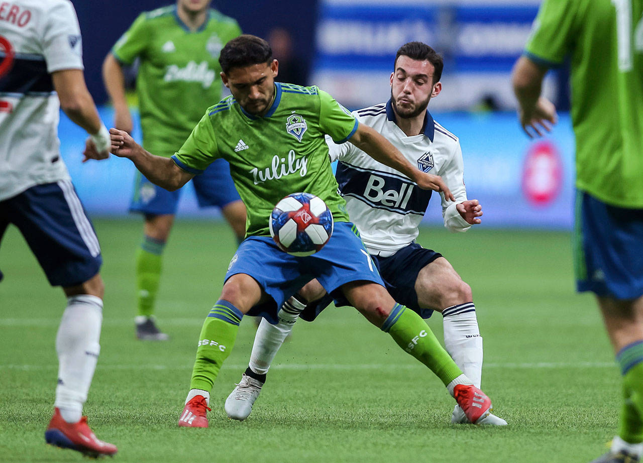The Sounders’ Cristian Roldan (7) plays the ball near the Whitecaps’ Russell Teibert during the second half of an MLS match on March 30, 2019, in Vancouver, British Columbia. (Ben Nelms / The Canadian Press via AP)