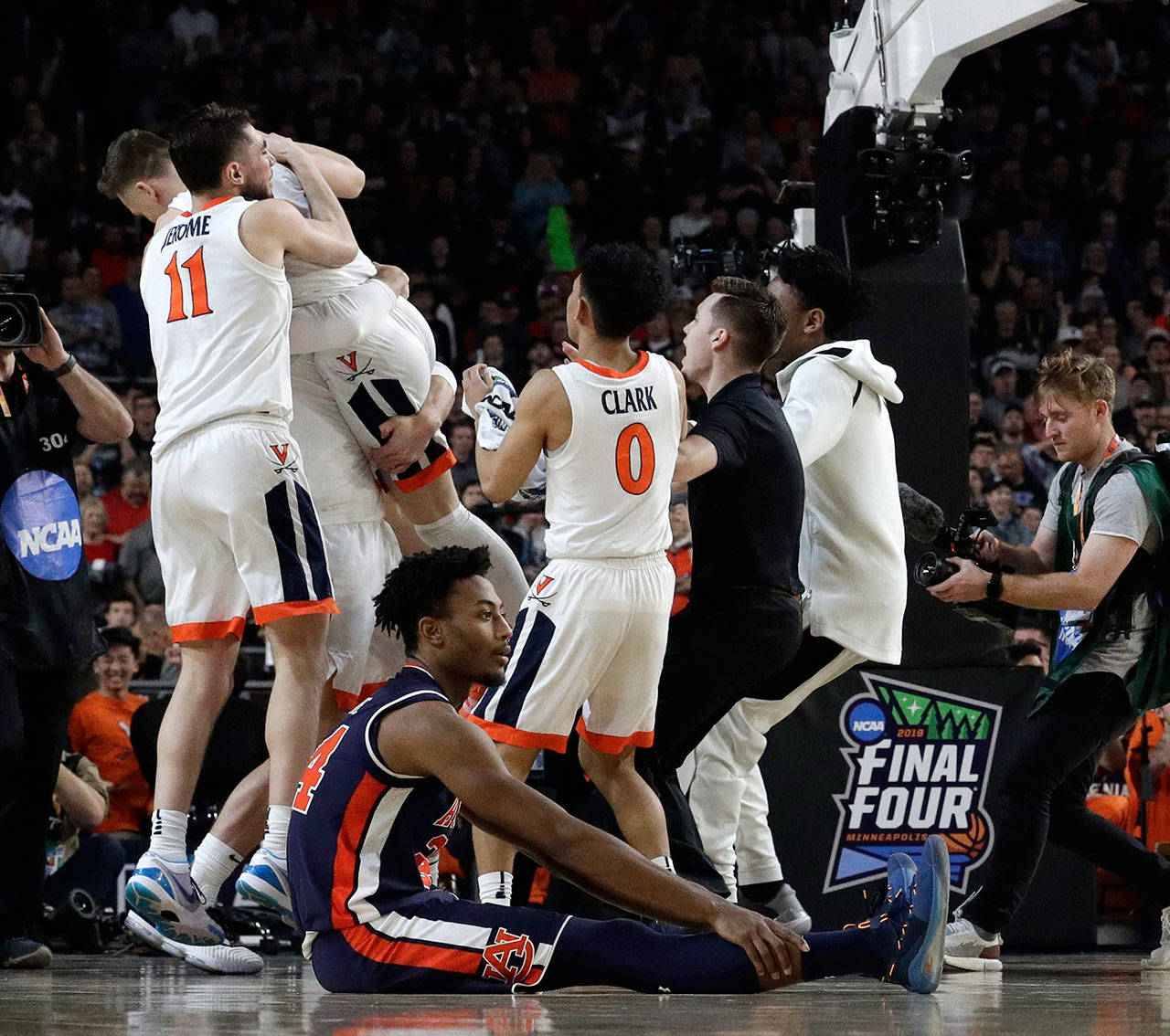 Virginia players celebrate as Auburn’s Anfernee McLemore (24) sits on the floor after the Cavaliers beat the Tigers 63-62 in the Final Four on April 6, 2019, in Minneapolis. (AP Photo/David J. Phillip)