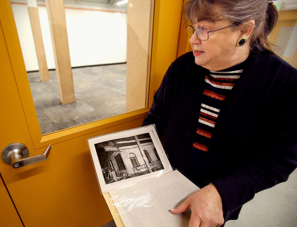 With old photos, including some of The Everett Daily Herald fire in 1956, Everett Museum of History Executive Director Barbara George shows off renovations being done on the museum’s building Thursday. (Dan Bates / The Herald)
