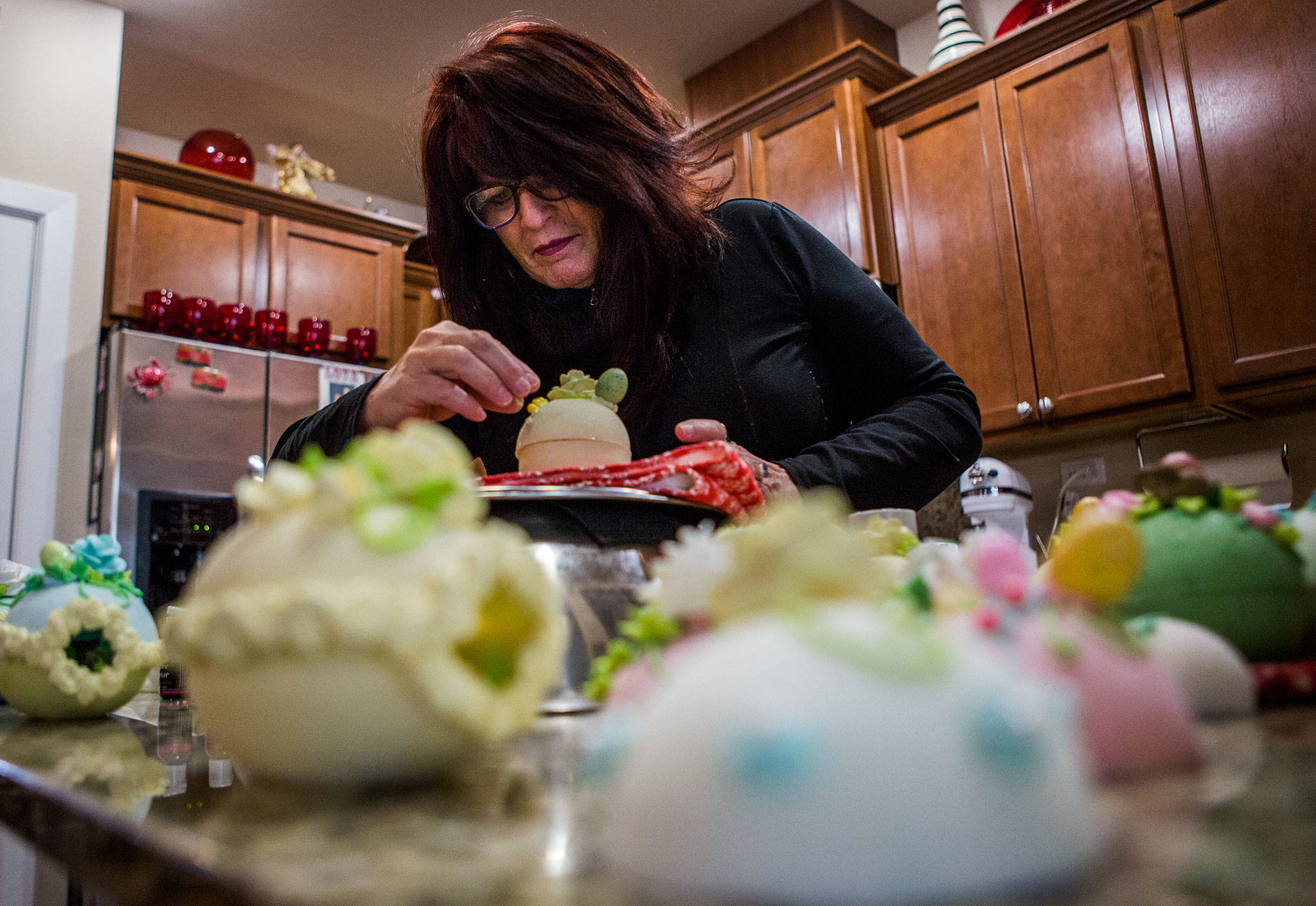 Darla Aiken places celebration pearls on the royal icing designs covering one of her sugar eggs at her home in Lynnwood. (Olivia Vanni / The Herald)