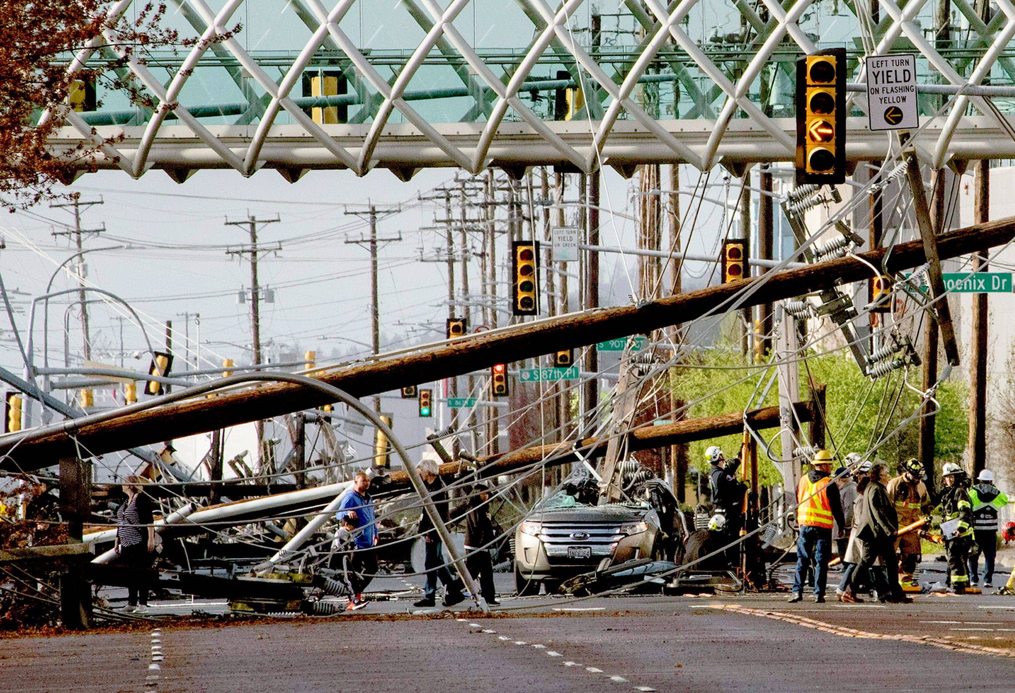 A SeaTac couple was trapped in their car (center) for more than an hour after 26 utility poles came crashing down on East Marginal Way in Seattle on Friday. (Ellen M. Banner/The Seattle Times via AP)