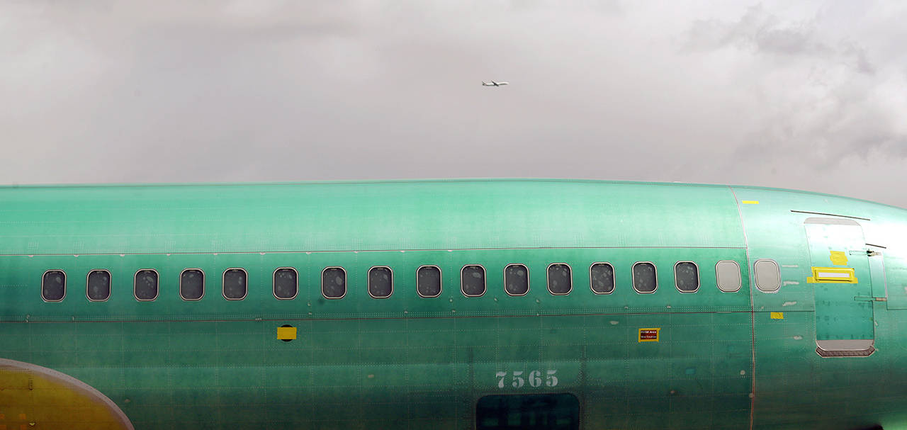 AP Photo/Elaine Thompson                                 A Boeing 737 fuselage, eventually bound for Boeing’s production facility in nearby Renton, sits on a flatcar rail car at a rail yard as a jet flies past overhead Tuesday in Seattle.