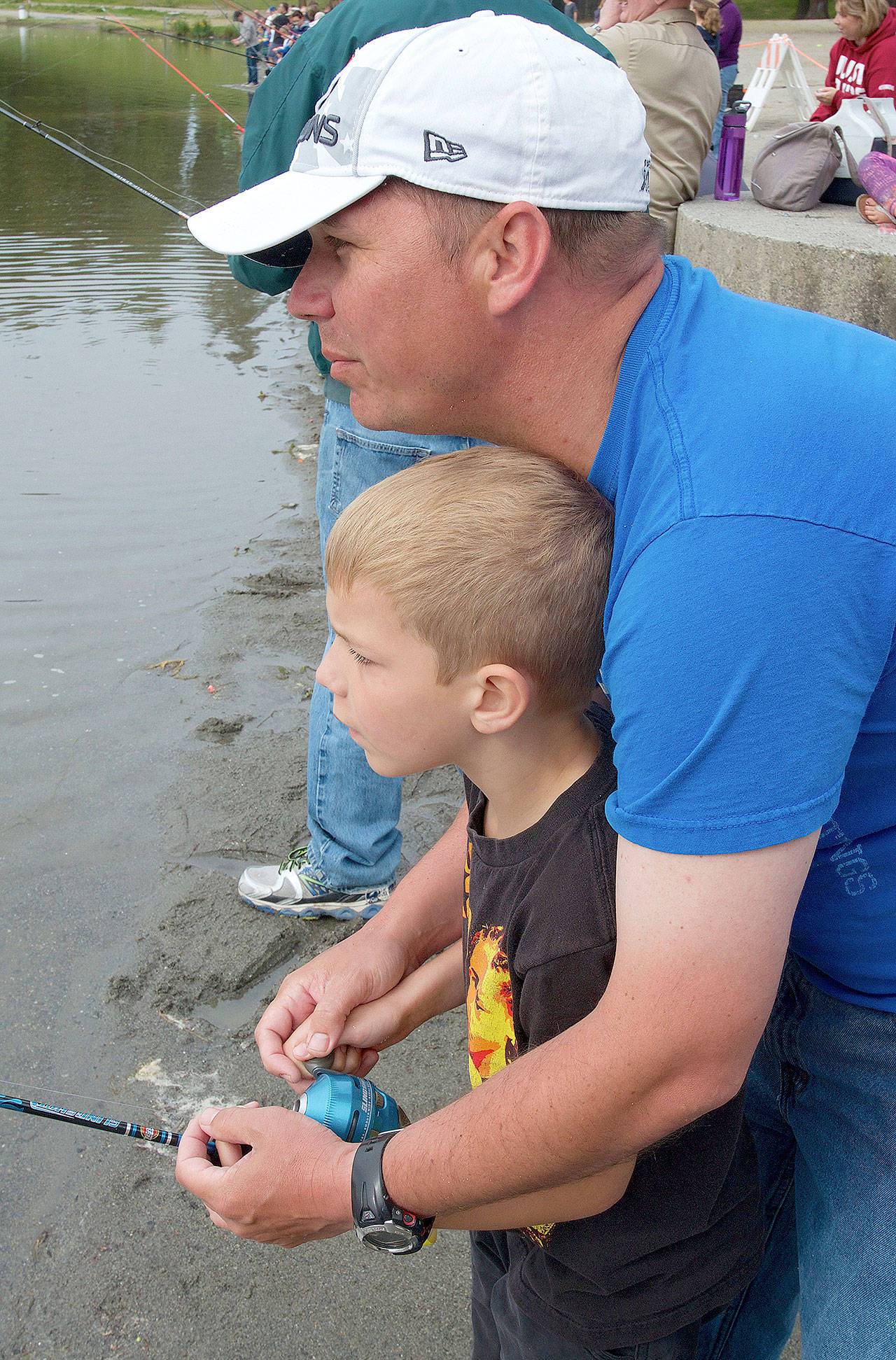 A dad helps his son try to hook up with a trout at the Everett fish-in. (Mike Benbow)