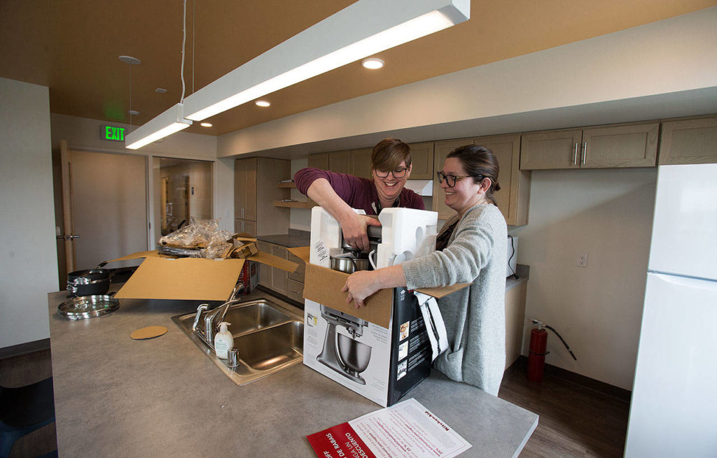 Cocoon House’s Rachel Mathieson and Sarah Ciraci unbox a mixer in one of three pods at the new shelter for young people who are homeless Tuesday on Colby Avenue in Everett. (Andy Bronson / The Herald)
