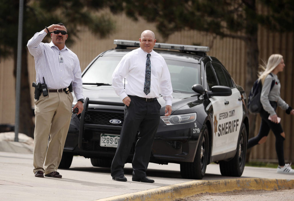 Columbine High School principal Scott Christy (right) joins an officer in watching as students leave the school late Tuesday in Littleton, Colorado. (AP Photo/David Zalubowski)
