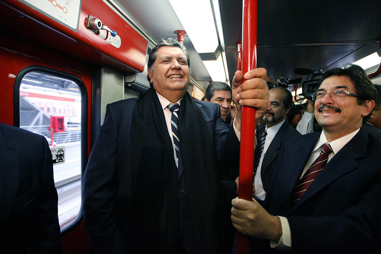 In this 2011 photo, Peru’s then-outgoing President Alan Garcia (left), rides the Line 1 electrical train system in Lima, Peru. A lawyer for the former Peruvian President Alan García said Wednesday the leader shot himself before being detained by police amid allegations he received illegal payment from Brazilian construction giant Odebrecht. (AP Photo/Martin Mejia, File)