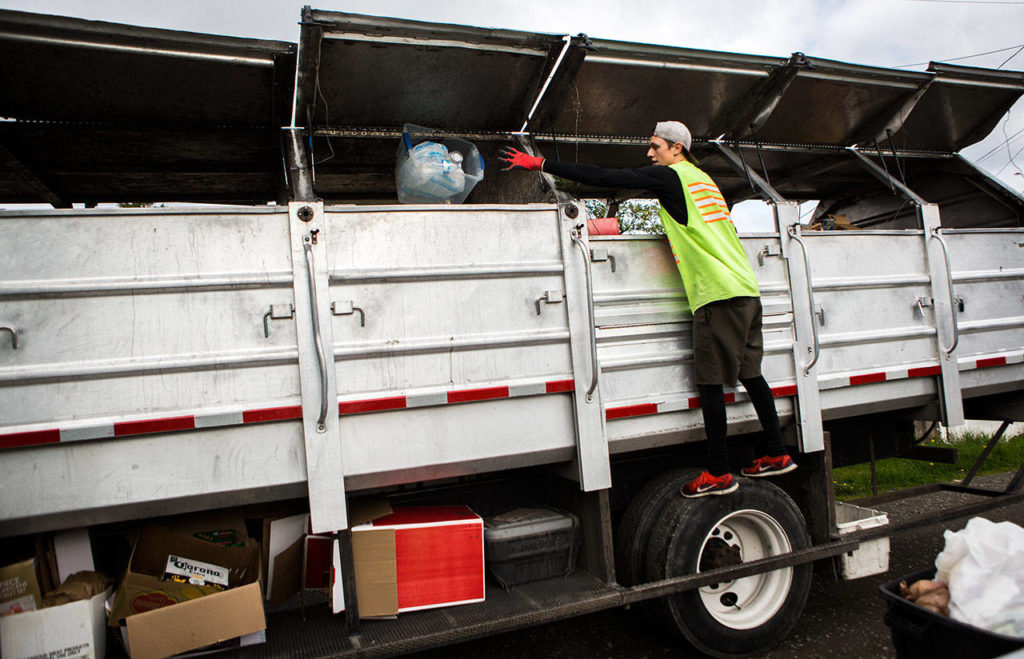 Jeremy Youngren throws a bin to his plastics section of his truck during his route on Wednesday, April 24, 2019 in Everett, Wash. (Olivia Vanni / The Herald)
