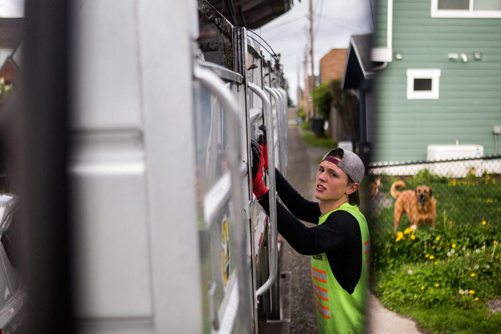 Jeremy Youngren raises the walls of his truck as the sections begin to fill up during his route on Wednesday, April 24, 2019 in Everett, Wash. (Olivia Vanni / The Herald)
