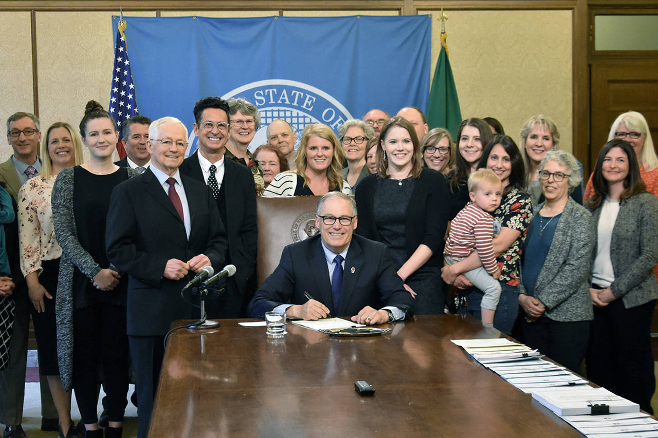 Cancer patient Nikki Dziedzic holds her son as Gov. Jay Inslee signs a bill that protects ACA health insurance practices such as pre-existing conditions. (Office of the Governor photo)