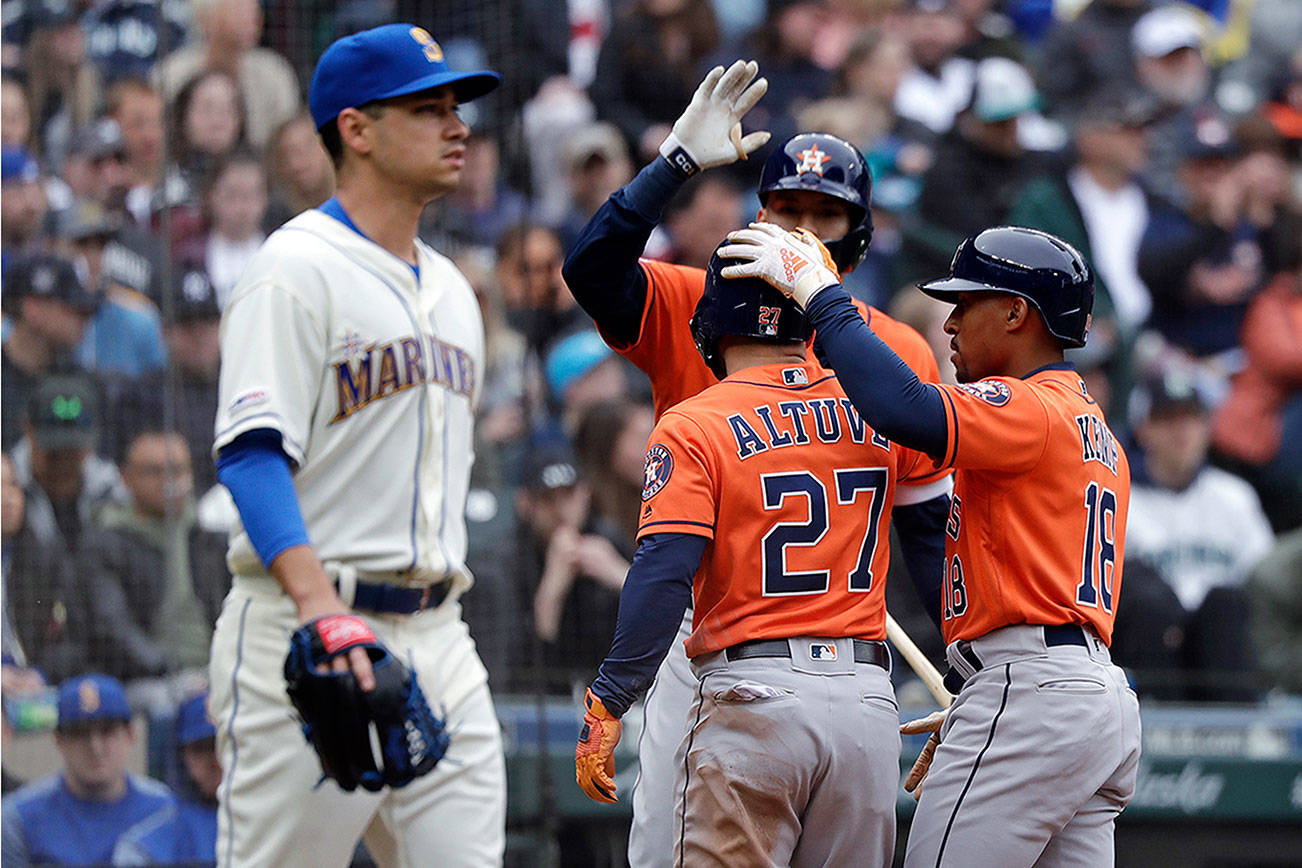 Seattle Mariners starting pitcher Marco Gonzales, left, heads back to the mound as Houston Astros’ Jose Altuve (27) and Tony Kemp (18) celebrate scoring with Carlos Correa in the sixth inning of a baseball game Sunday, April 14, 2019, in Seattle. (AP Photo/Elaine Thompson)
