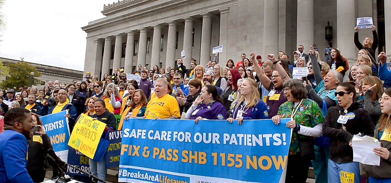Travis Elmore (in yellow shirt), a registered nurse for 14 years now representing the Washington State Nurses Association, addresses a rally on the steps of the Legislative building in Olympia on Wednesday. They were on hand to support HB 1155, legislation that concerns mandatory meal and rest break times for certain health care employees. (Steve Bloom / The Olympian)