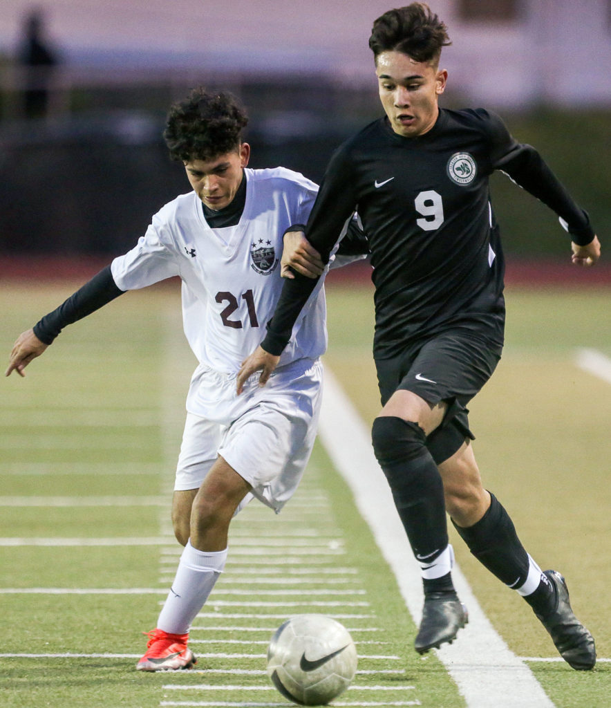 Cascade’s Gennadiy Yaychenya (left) and Jackson’s Oliver Giessler run down the ball Friday night at Everett Memorial Stadium in Everett. (Kevin Clark / The Herald)
