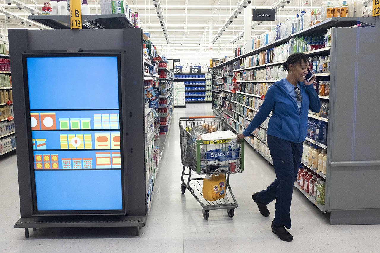 A customer pulls her shopping cart past an information kiosk at a Walmart Neighborhood Market on Wednesday in Levittown, New York. (AP Photo/Mark Lennihan)