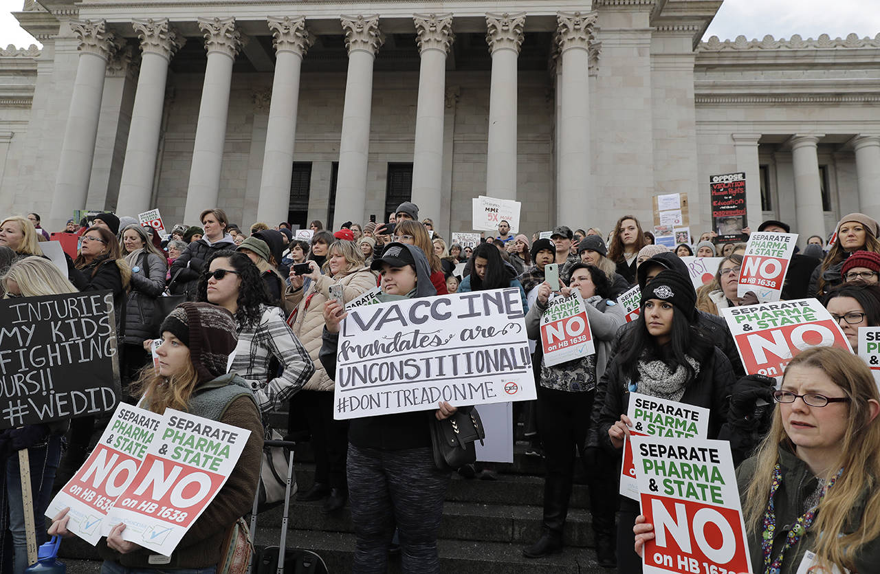People hold signs at a February 8 rally held in opposition to a proposed bill that would remove parents’ ability to claim a philosophical exemption to opt their school-age children out of the combined measles, mumps and rubella vaccine, at the Capitol in Olympia. (AP Photo/Ted S. Warren, file)