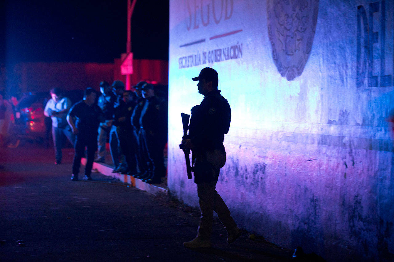 A Federal Police officer stands guard outside an immigration detention center in Tapachula, Chiapas state, Mexico, late Thursday. A large group of mainly Cuban migrants escaped on foot from the immigration detention center on Mexico’s southern border in the largest mass escape in recent memory. Later, about half of the group returned voluntarily. (AP Photo/Moises Castillo)