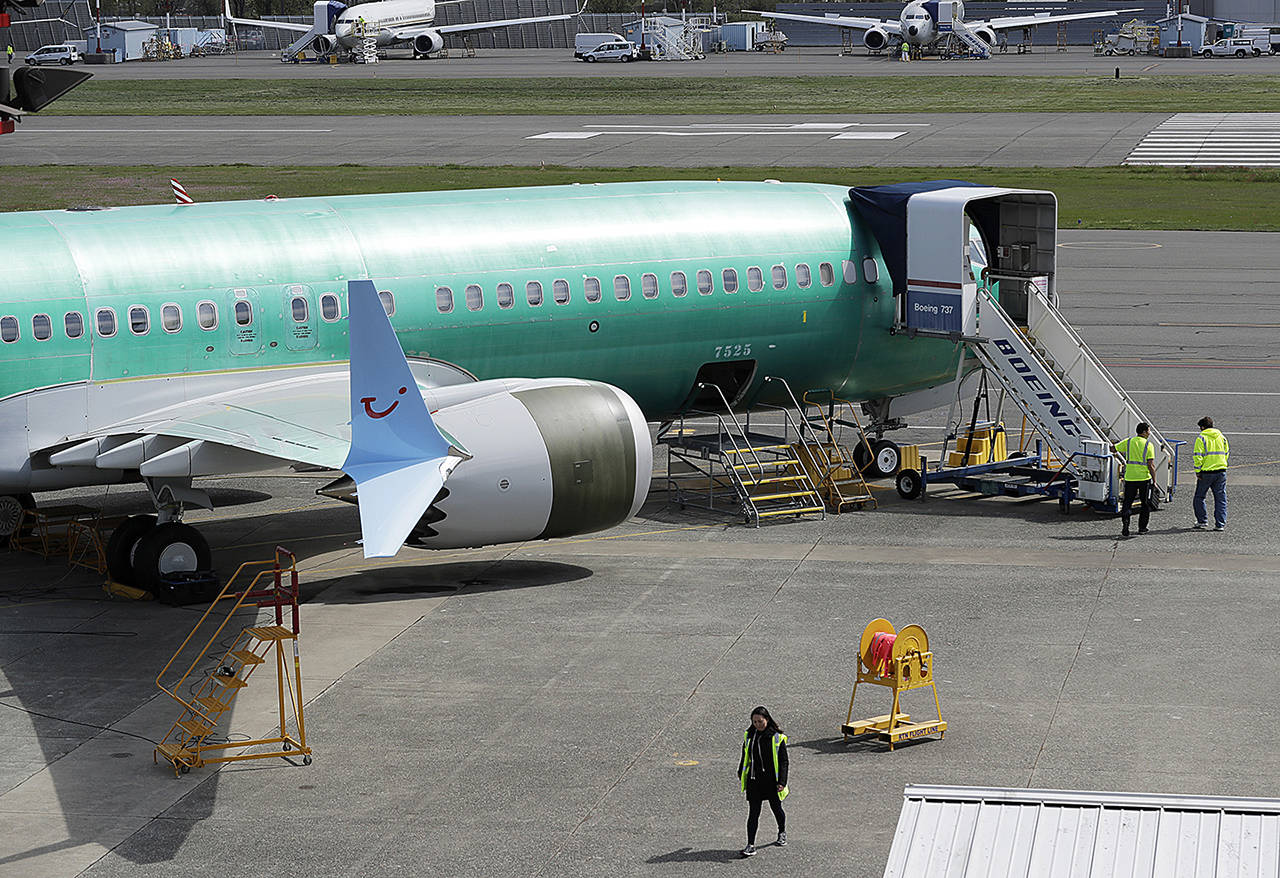 Workers walk past a Boeing 737 MAX 8 TUI fly airplane being built for TUI Group at Renton Municipal Airport next to Boeing’s assembly facility in Renton on Friday. (AP Photo/Ted S. Warren)