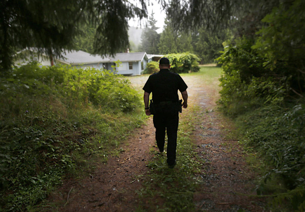 Arlington police Sgt. Rob Martin walks past where Robert Endrizzi lie (behind berm on left) near the drive to his home, firing a rifle at people and vehicles on Jim Creek Road, until he was killed by the SWAT team Martin led in September 2012. (Dan Bates / The Herald)
