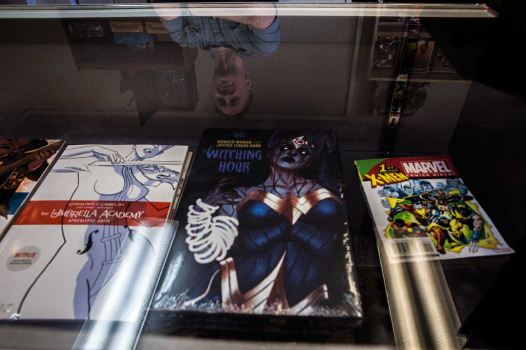 Russ Bright looks out over one the glass display cases at Mill Geek Comics. (Olivia Vanni / The Herald)
