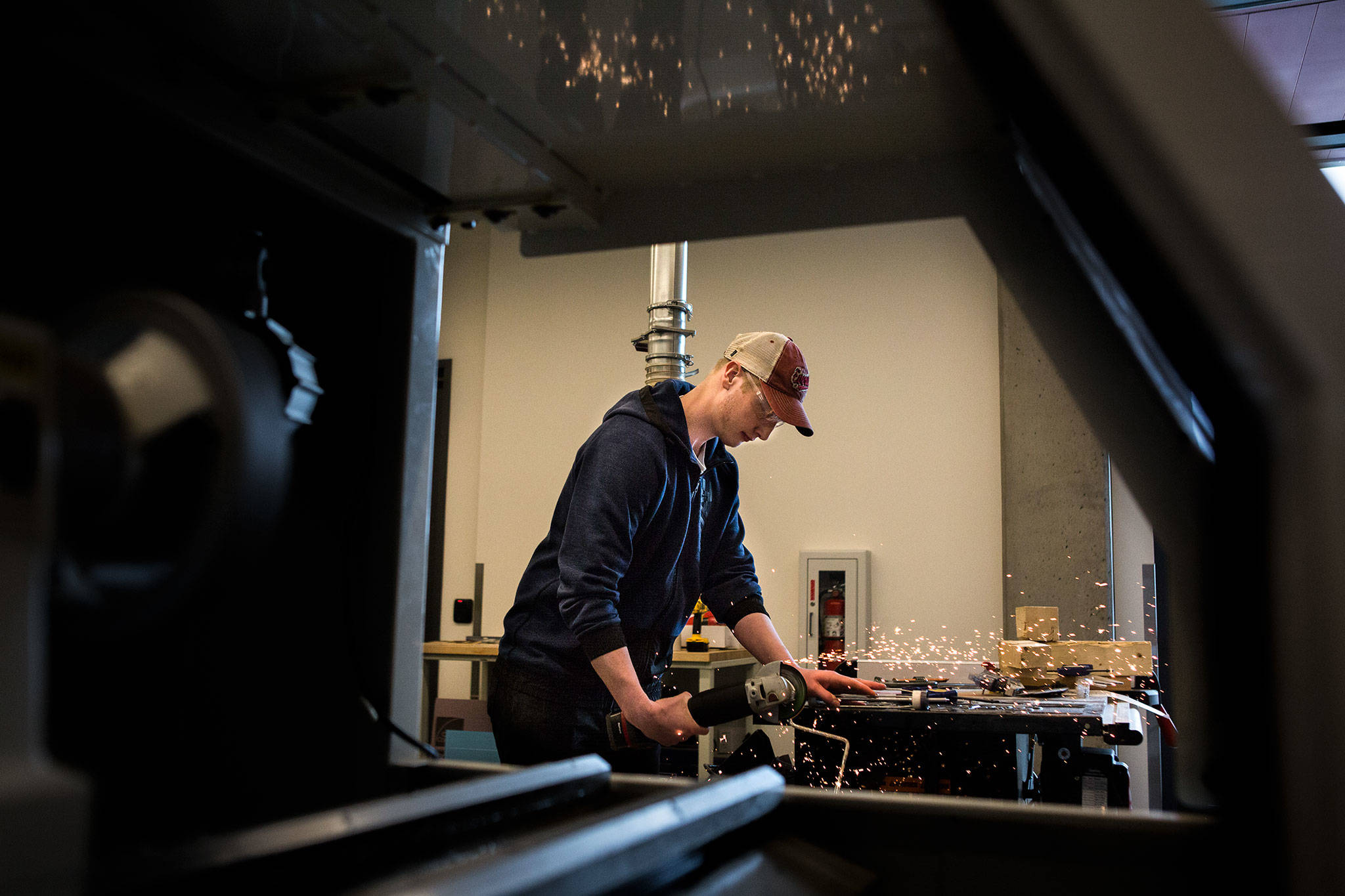 Isaac Alexander, 20, saws off the handle of a paint roller to be used to build his group’s toilet-paper-dispensing robot at TheLab@everett. (Olivia Vanni / The Herald)