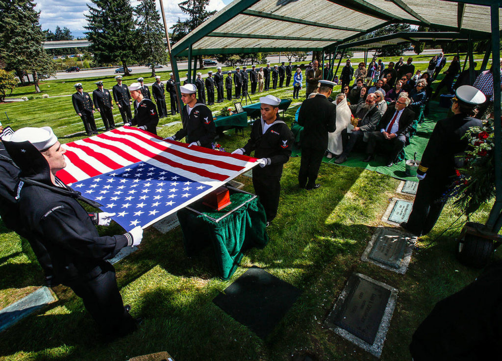 Sailors hold an American flag over the urn bearing Daniel Guisinger’s ashes before the Everett sailor is buried at Cypress Lawn Memorial Park on April 27. He was killed at Pearl Harbor, and his remains were recently identified using DNA. (Dan Bates / The Herald)
