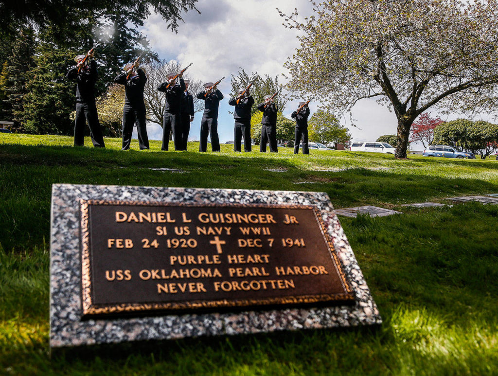 A ceremonial rifle team from Naval Base Kitsap fires three volleys for a 21-gun salute April 27 at Cypress Lawn Memorial Park. The grave marker for Daniel Guisinger Jr., an Everett sailor killed at Pearl Harbor, awaits placement at his grave. (Dan Bates / The Herald)
