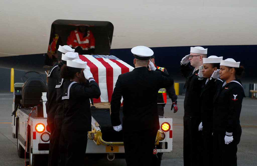 At Sea-Tac Airport on April 24, a Navy honor guard salutes as a casket bearing the remains of USS Oklahoma sailor Daniel Guisinger is removed from an airliner. (Dan Bates / The Herald)
