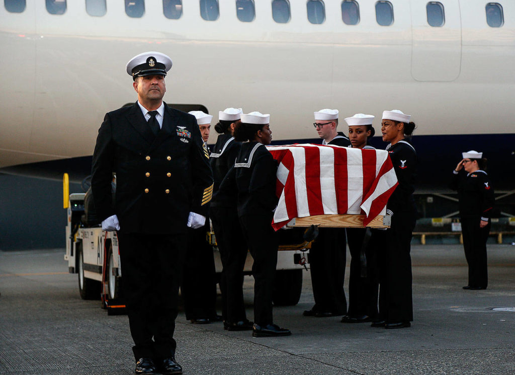Navy Chief Juan Nevarez, of Naval Base Kitsap, stands at attention as an honor guard prepares to carry the casket holding Daniel Guisinger’s remains to a waiting hearse at Sea-Tac Airport. (Dan Bates / The Herald)
