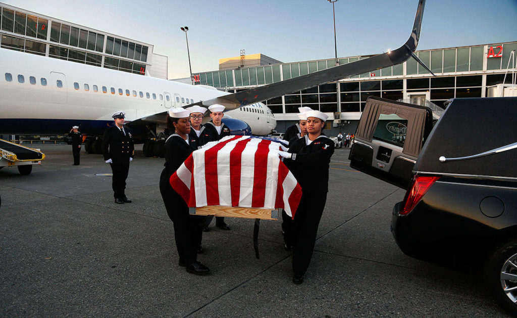 A Navy honor guard carries the flag-draped casket holding the remains of Everett sailor Daniel Guisinger, who was killed at Pearl Harbor. Passengers aboard the Delta Air Lines flight that carried the casket remained on the plane during the ceremony. (Dan Bates / The Herald )
