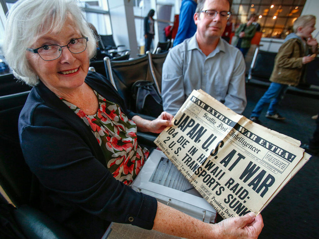 At Sea-Tac Airport, Judy Price holds a copy of the Dec. 8, 1941, Seattle Post-Intelligencer that announced a nation at war. Daniel Guisinger, her mother’s brother, was killed in the attack on Pearl Harbor that launched the United States into World War II. (Dan Bates / The Herald)
