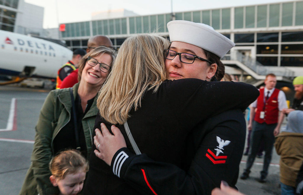 A Navy escort, Hospital Corpsman 2nd Class Stephanie Kitchen, traveled on every flight of the journey that brought Daniel Guisinger’s remains home to Washington. Here, she hugs a family member as RuthAnn Hoeglund looks on at Sea-Tac Airport. (Dan Bates / The Herald)
