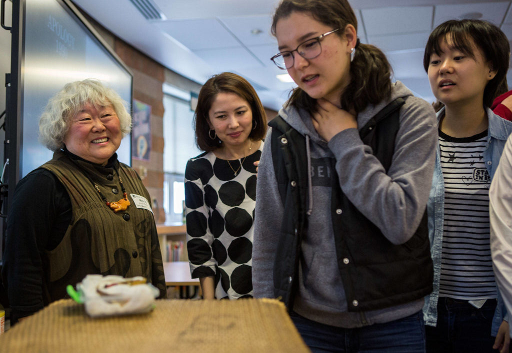 Judy Kusakabe smiles as students look at her artifacts and internment camp materials after her talk at Kamiak High School. (Olivia Vanni / The Herald)

