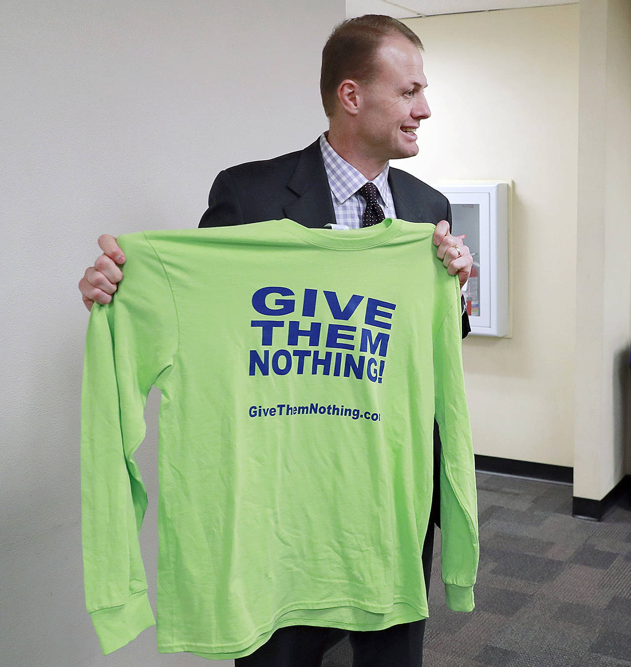 Initiative activist Tim Eyman holds a T-shirt promoting his initiative that would limit pay raises for elected officials, following his appearance in Thurston County Superior Court on Feb. 22 in Olympia. (AP Photo/Ted S. Warren, file)