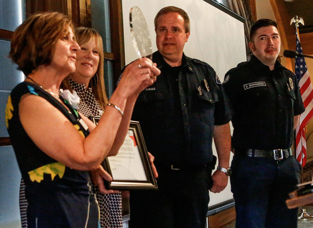 Assistance League of Everett ‘s Caryl de Jong (left) and Rock Dorsey present the National Operation School Bell award to North County Fire/EMS Lt. Gary Lingel and Gabe Buonassissi Thursday at Everett Golf and Country Club. (Dan Bates / The Herald)
