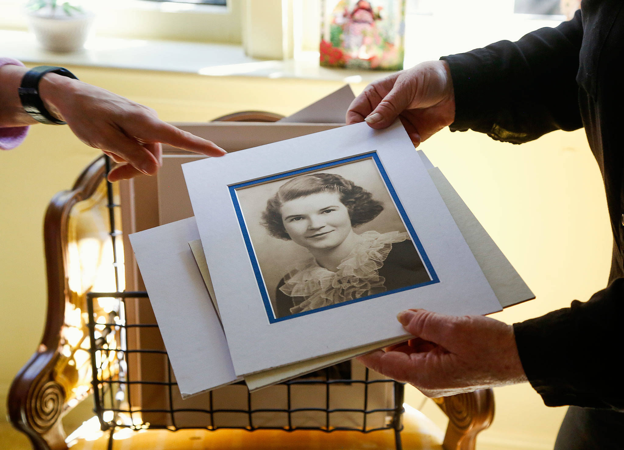 In the north Everett home where she and her sister Margaret “Mugsy” Duryee grew up, Maureen Duryee sorts through photographs of their mother Mary Duryee. This portrait was Mary’s Everett High School 1935 graduation portrait. She died April 22 at age 100. (Dan Bates / The Herald)
