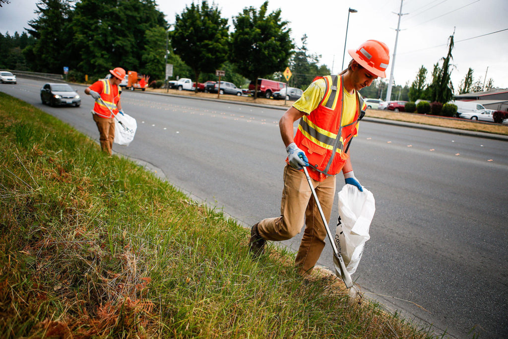 Seasonal Snohomish County workers Kyle Schuman (right) and Dakota Scherrer pick up trash along Marine Drive in Marysville on June 28, 2017. (Ian Terry / Herald file)
