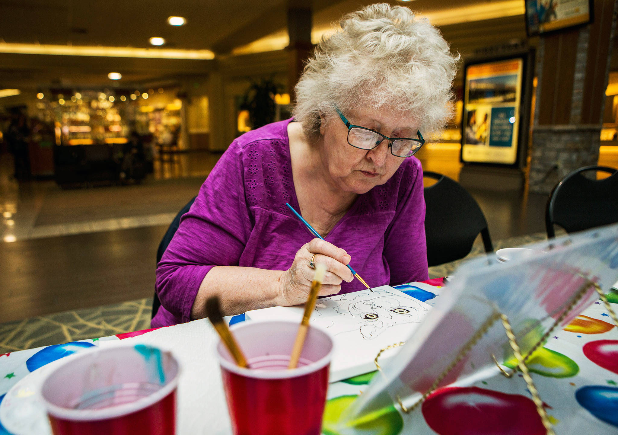 Linda Suby works on a cat painting during Shelter Pet Portraits at the Everett Mall. The cause raises money for animals needing homes and sponsors. Painting sessions are free. (Olivia Vanni / The Herald)