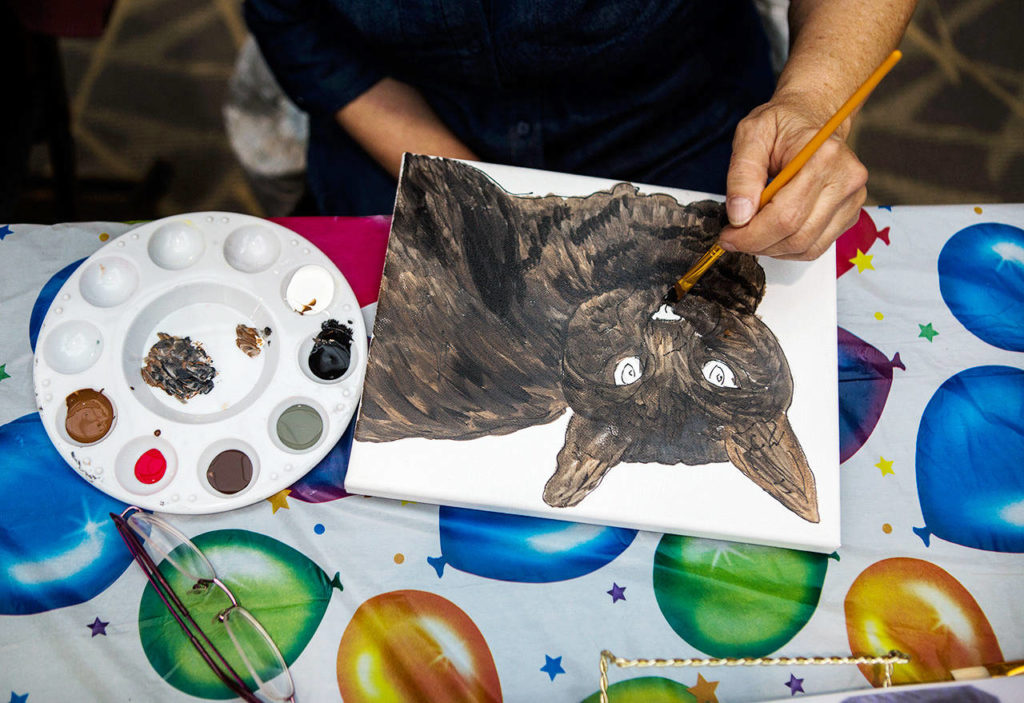 Marilyn Blackburn works on a portrait of a shelter cat named Lilly during a Paws With Cause session at the Everett Mall. (Olivia Vanni / The Herald)
