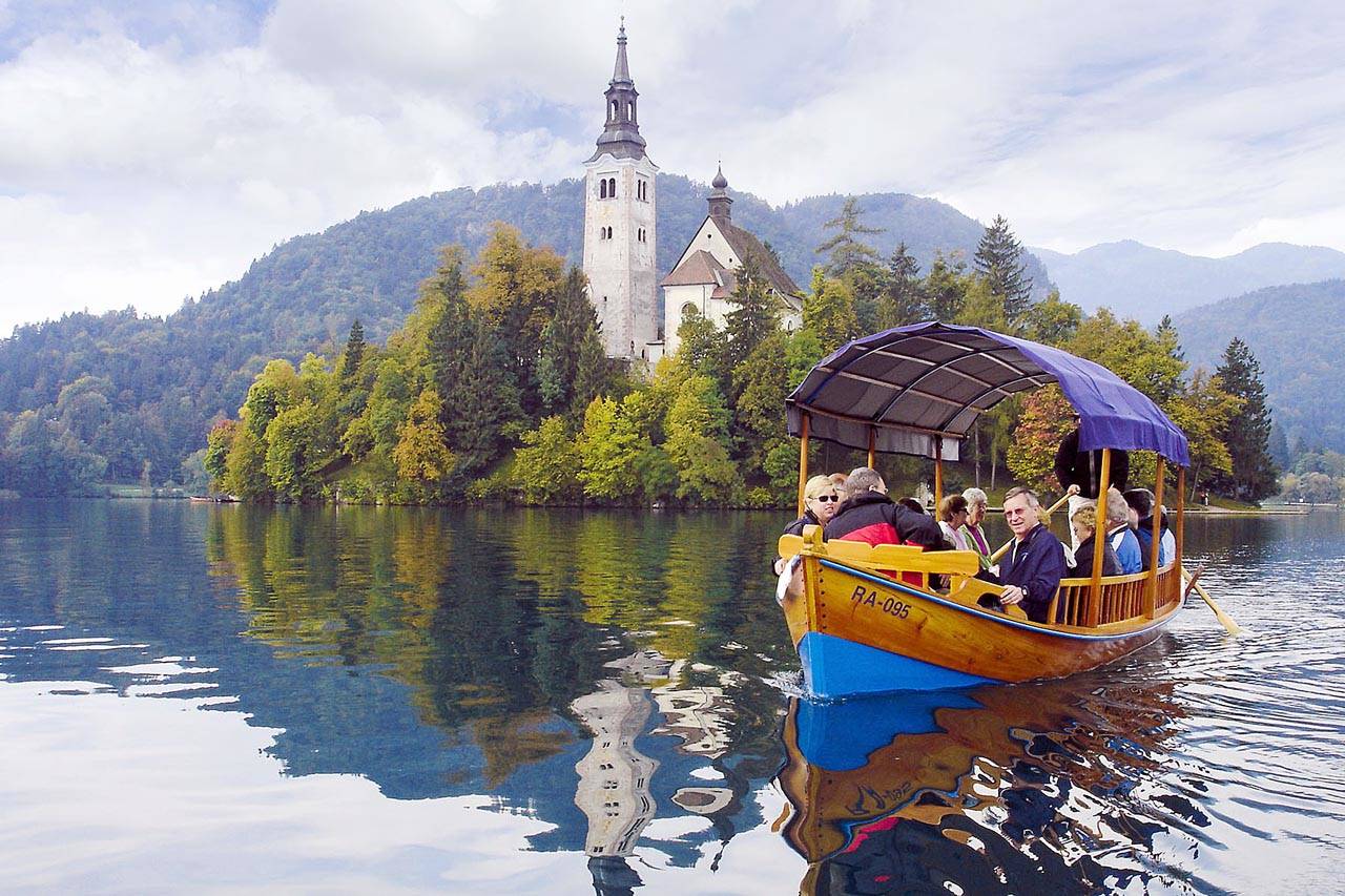 Visitors enjoy a scenic ride to a Lake Bled island on a traditional pletna boat. (Rick Steves’ Europe)