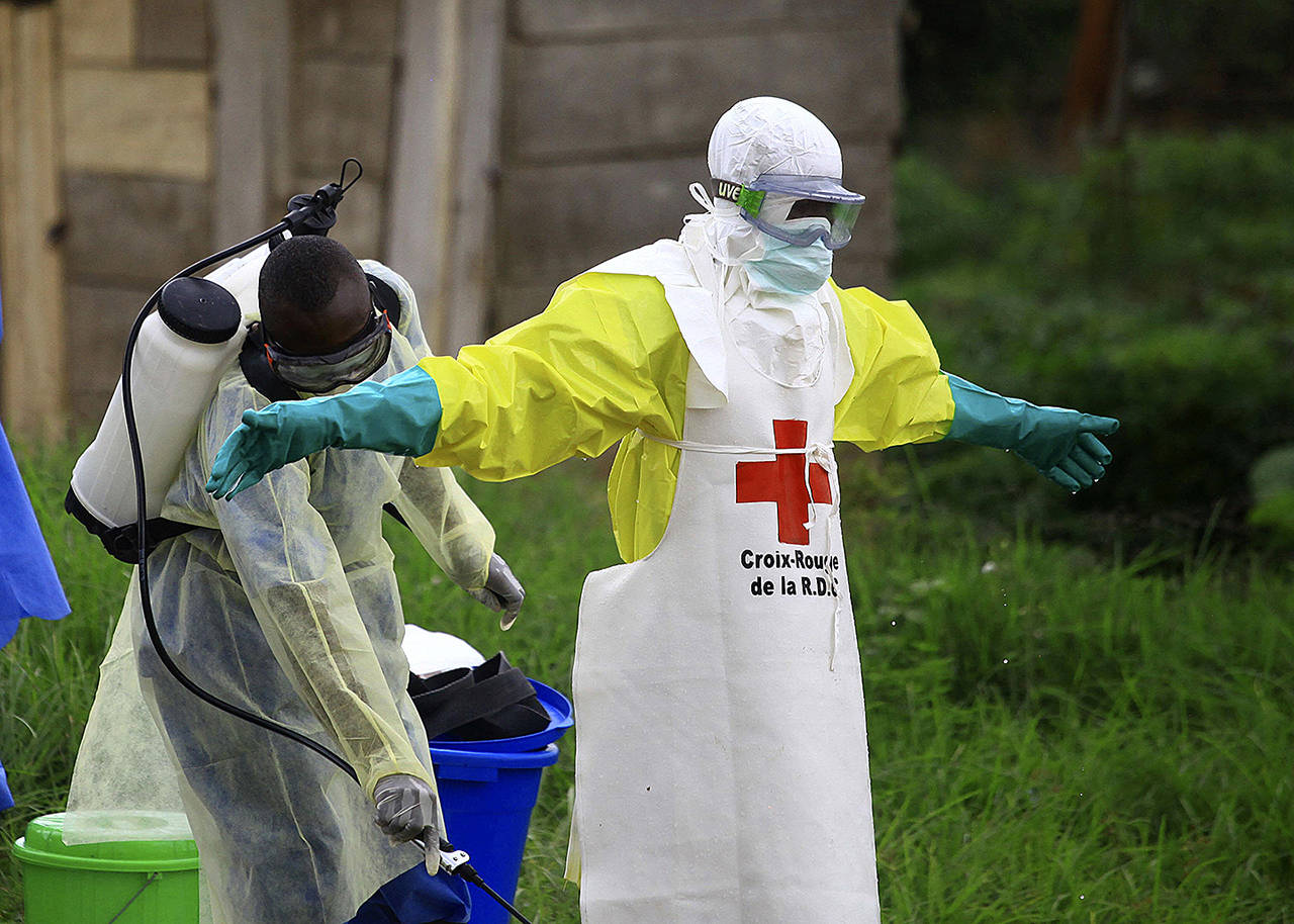 In this 2018 photo, a health worker sprays disinfectant on his colleague after working at an Ebola treatment center in Beni, eastern Congo. (AP Photo/Al-hadji Kudra Maliro, File)