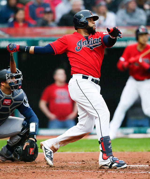 The Indians’ Carlos Santana hits a two-run home run as Mariners catcher Omar Narvaez (left) looks on during the eighth inning of a game on May 4, 2019, in Cleveland. (AP Photo/Ron Schwane)