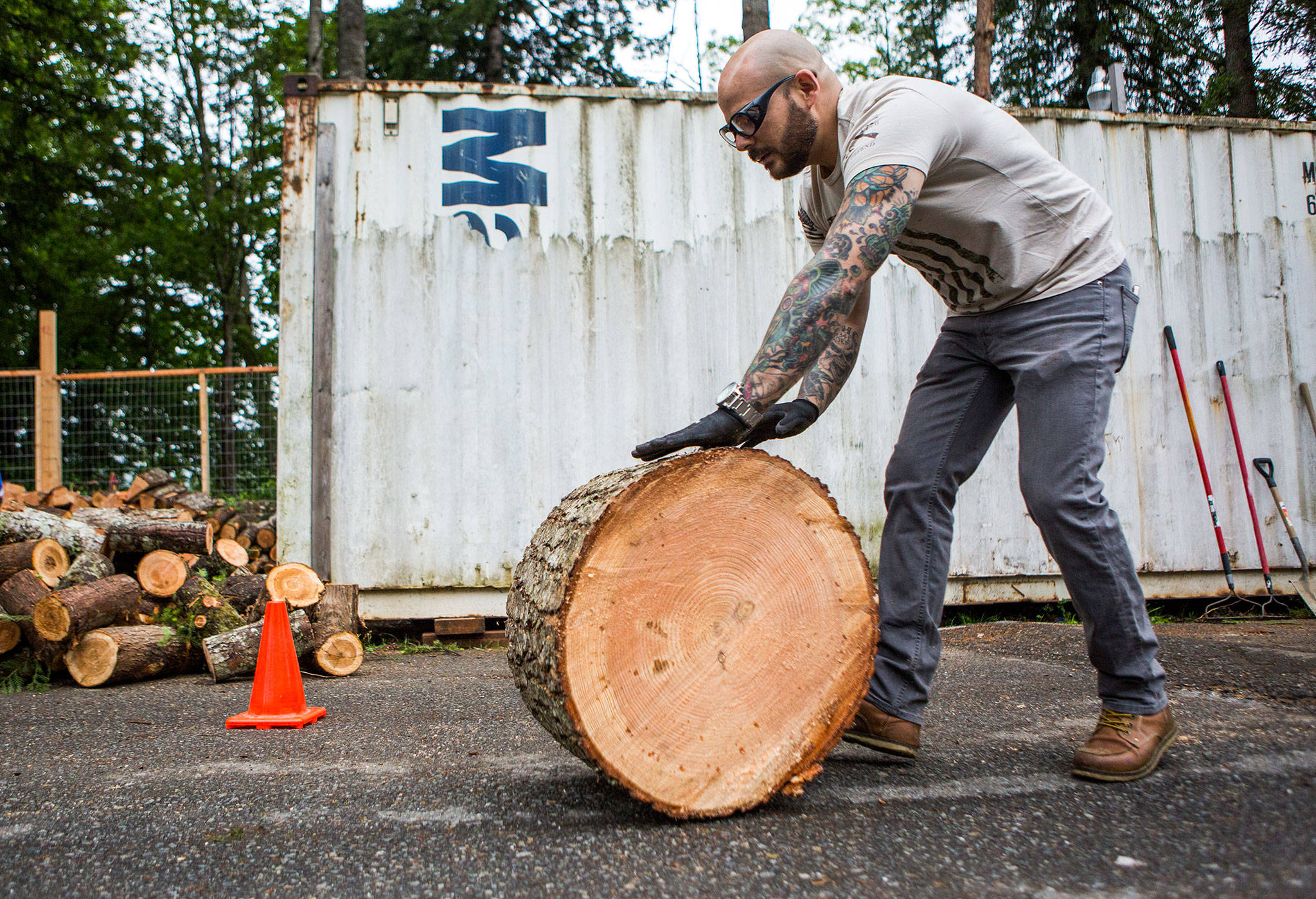 Dustin Comey, of Everett, who served in the Marines, rolls a log from the building site during a Habitat for Humanity Veterans Build event on Saturday in Gold Bar. (Olivia Vanni / The Herald)