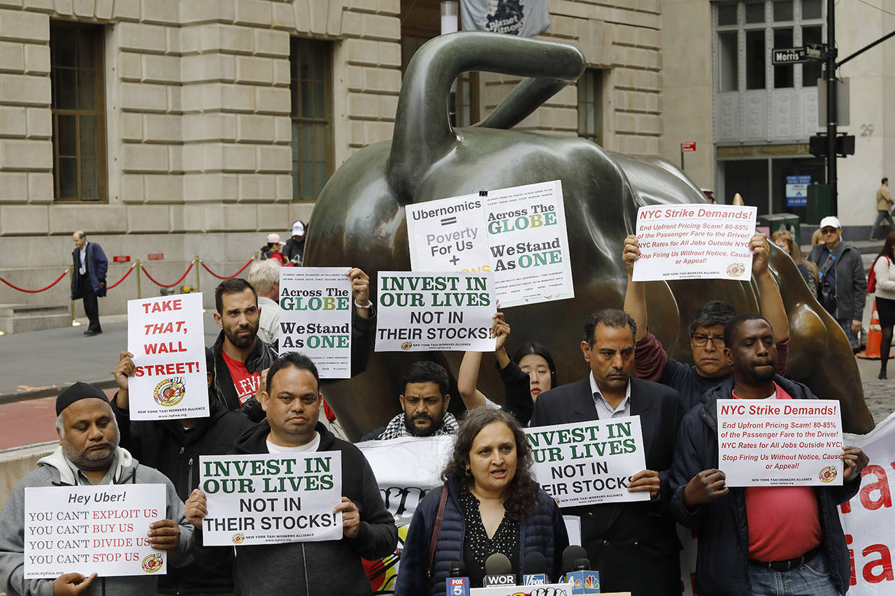 Uber drivers protest next to the Charging Bull statue in New York’s financial district Wednesday. (AP Photo/Mark Lennihan)