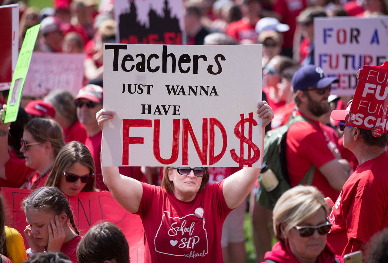 Thousands of Oregon teachers and education supporters march Wednesday in Portland. Tens of thousands of teachers across Oregon walked off the job Wednesday to demand more money for schools, holding signs and wearing red shirts that have become synonymous with a nationwide movement pushing lawmakers to better fund education. (Beth Nakamura/The Oregonian via AP)