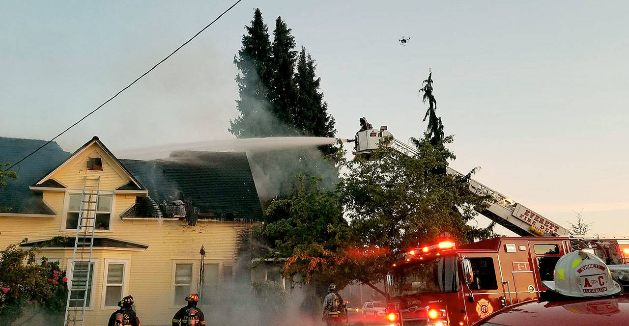 As a fire department drone hovers, water is poured on a burning house in the 2300 block of Harrison Avenue in Everett on Thursday. (Everett Fire Department)