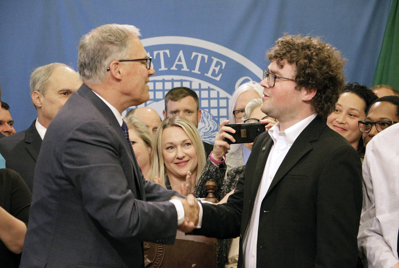 Gov. Jay Inslee shakes hands with Joshua Stuller after deeming him “Washingtonian of the Day” following the signing of a bill that seeks to speed up competency evaluations for defendants at jails, on Thursday in Olympia. Stuller, who advocated for the legislation, was released from Eastern State Hospital last year. (AP Photo/Rachel La Corte)