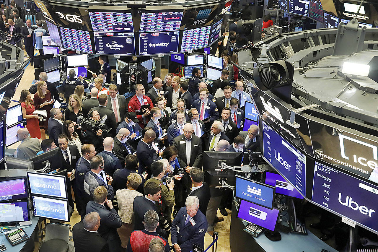 Stock traders gather around the post where Uber shares will begin trading during the company’s initial public offering at the New York Stock Exchange on Friday. (AP Photo/Richard Drew)