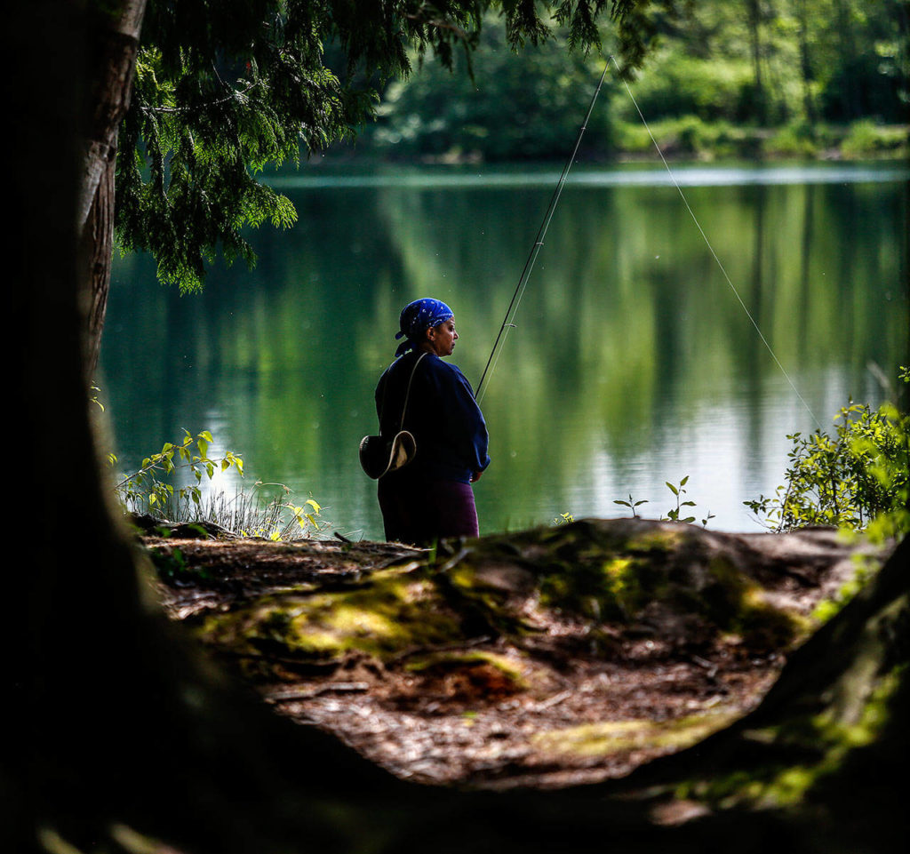 A Seattle woman enjoys fishing along the bank of the South Lake at Gissberg Twin Lakes county park in Marysville Wednesday. (Dan Bates / The Herald)
