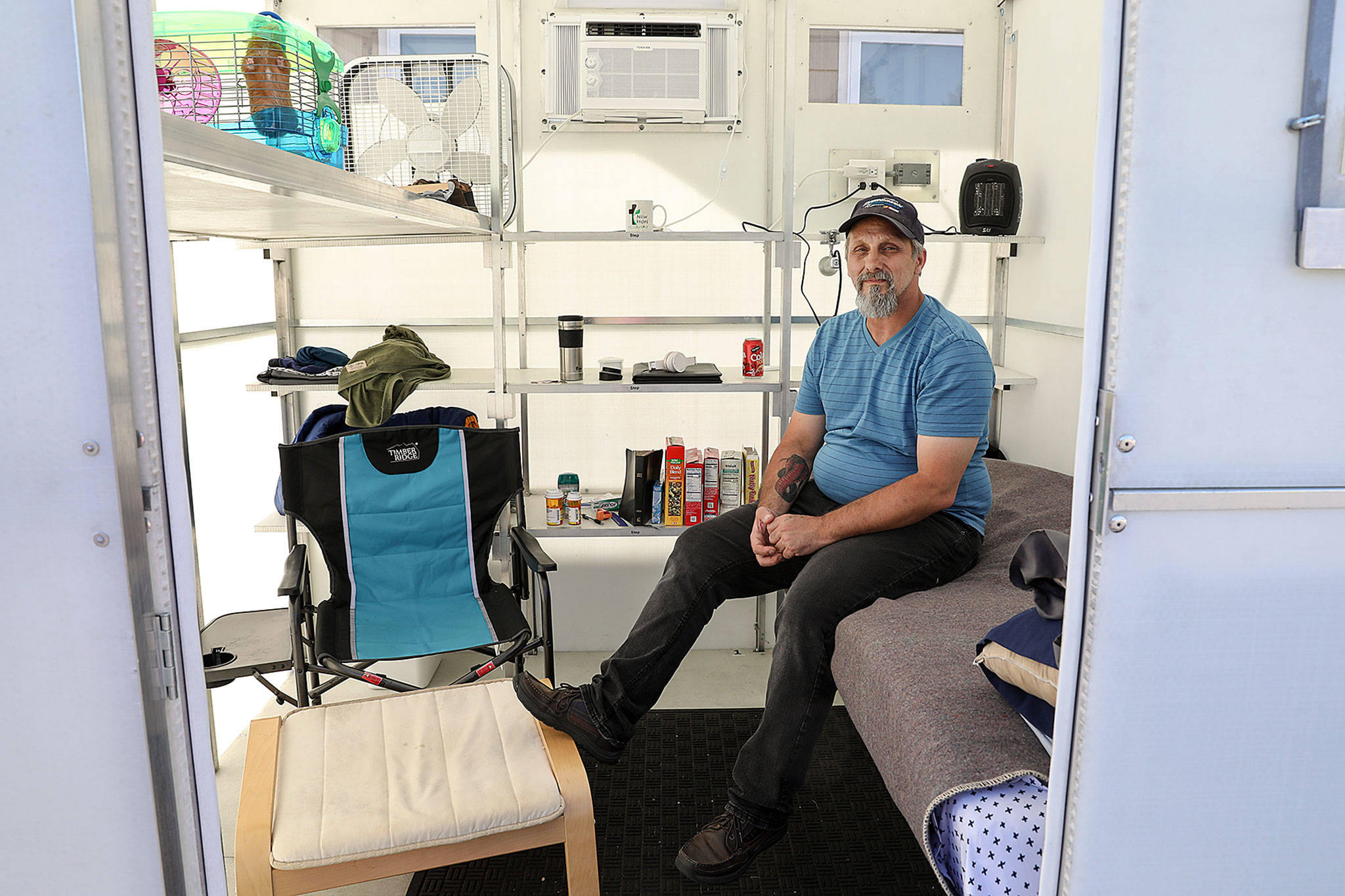 Roger Evans is working to bring a tiny home village for people experiencing homelessness to the Monroe church New Hope Fellowship. He sits in a demo unit that was brought to church grounds recently. (Lizz Giordano / The Herald)